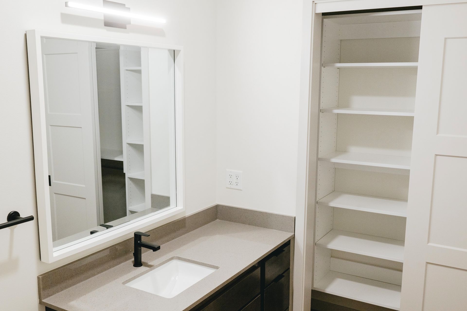 Bathroom with a vanity, large mirror, cabinet, and a tall storage unit at Revelry in Madison WI.