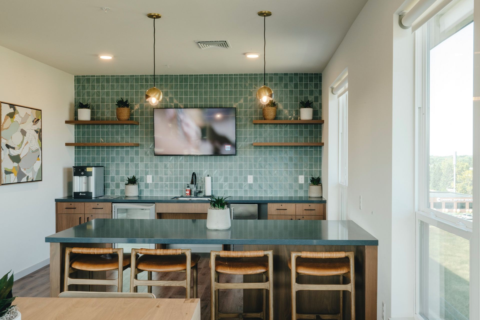 Kitchen area with teal backsplash, wooden shelves, TV, bar, and stools at Revelry in Madison WI.