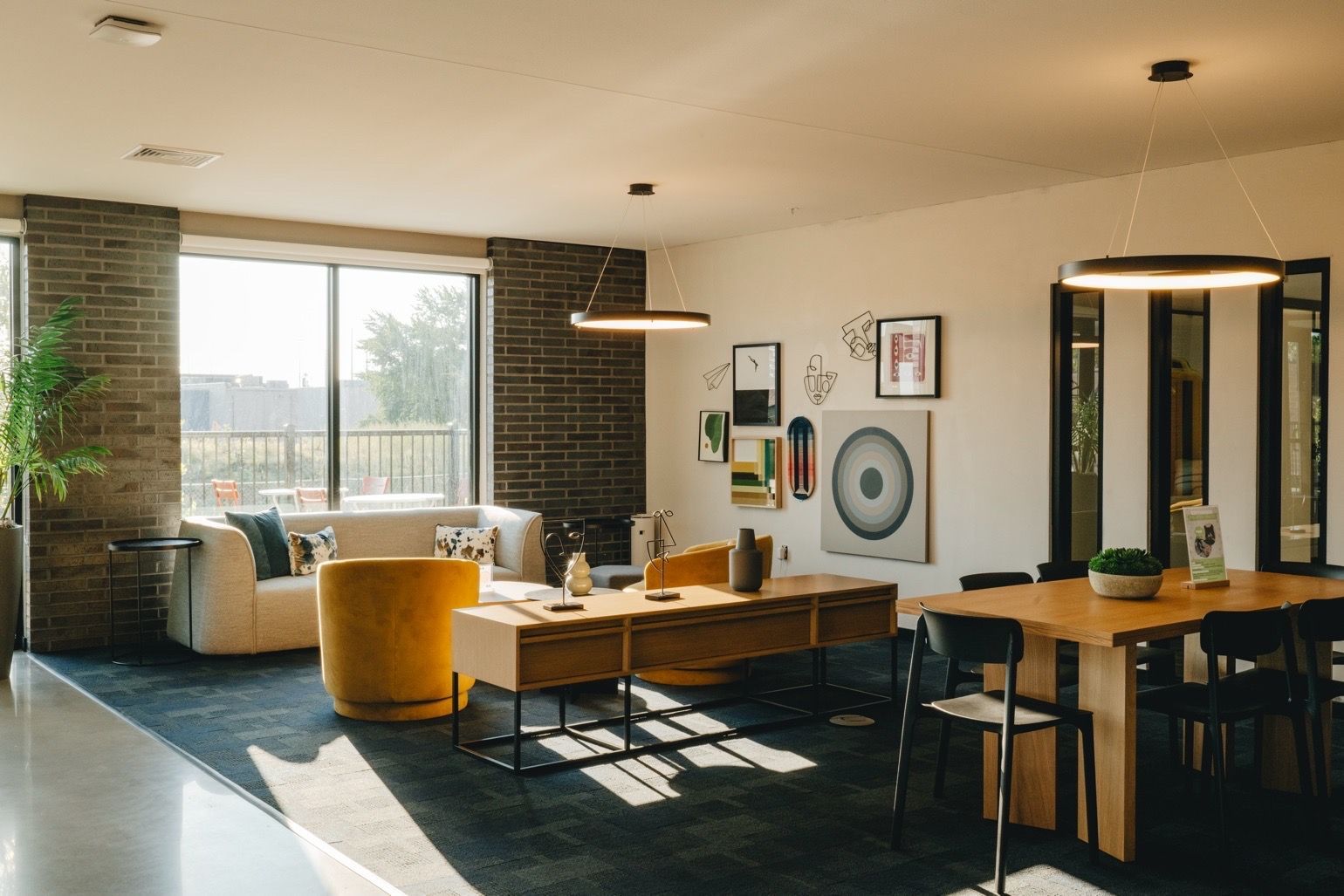 Modern living room with white walls, dark blue rug, and wooden furniture at Revelry in Madison WI.