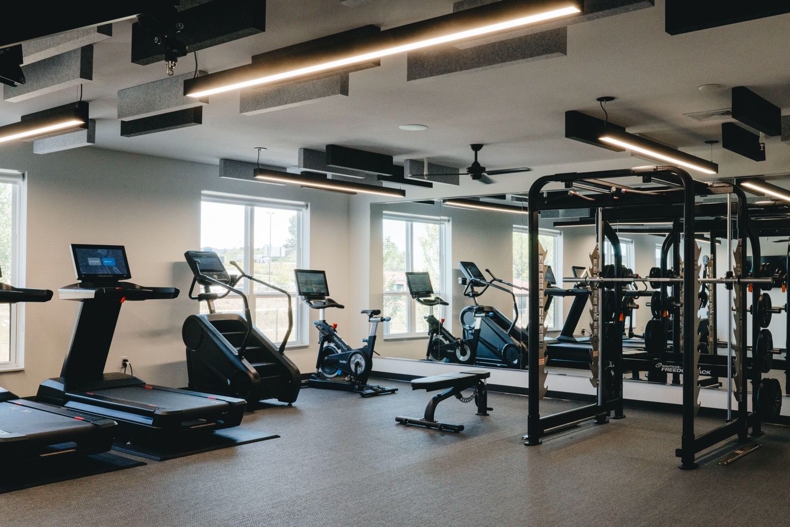 Gym interior with treadmills, stair climbers, exercise bikes, and weight machine.