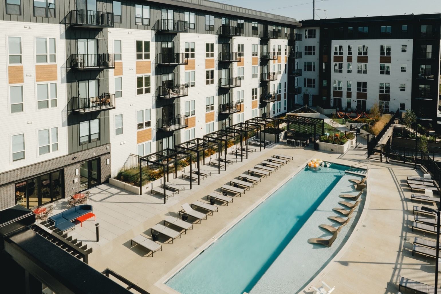 Apartment complex with a long swimming pool lined with lounge chairs at Revelry in Madison WI.
