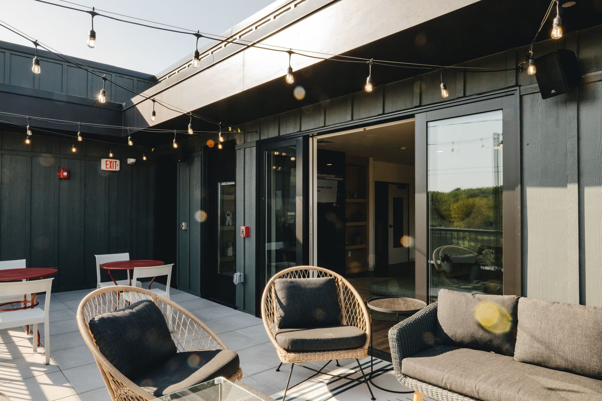 Rooftop patio with string lights, seating, and access to a building interior.