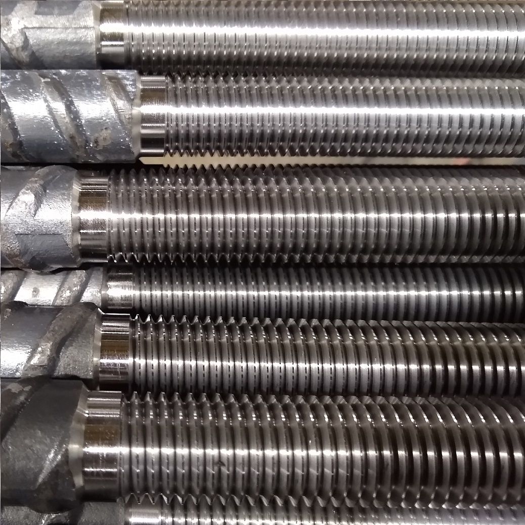 Close-up of several steel rebar pieces with helical threads.