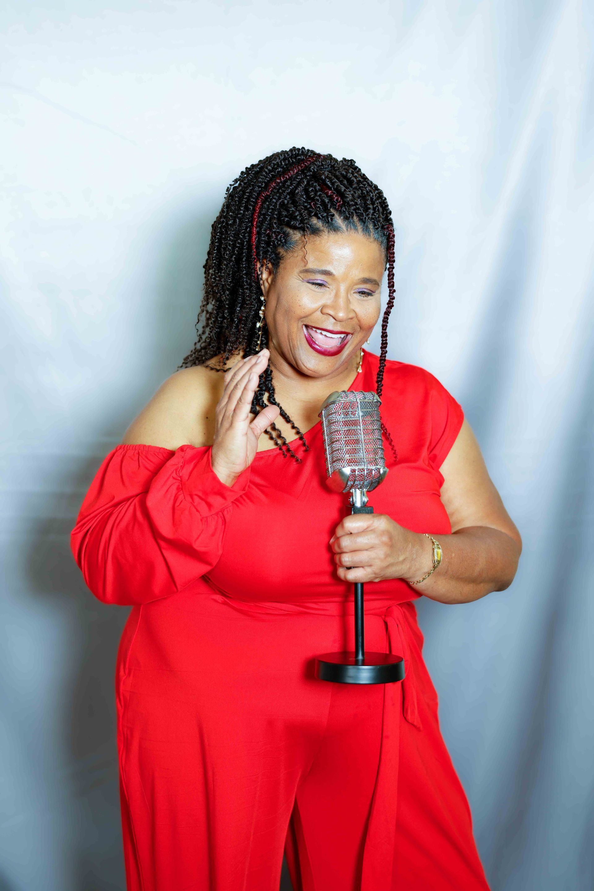 A woman in a red jumpsuit is holding a microphone.