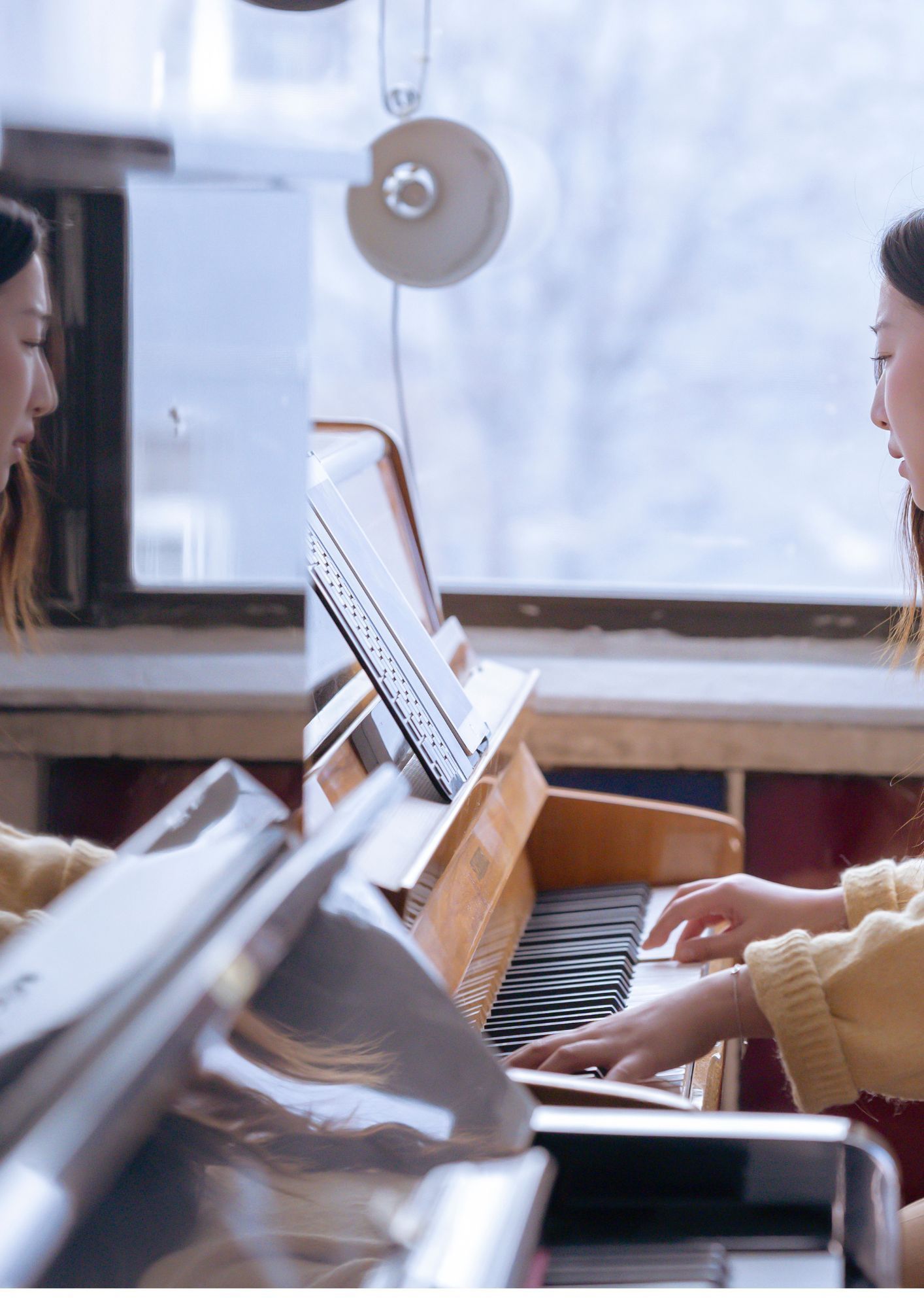 A woman is playing a piano in front of a window