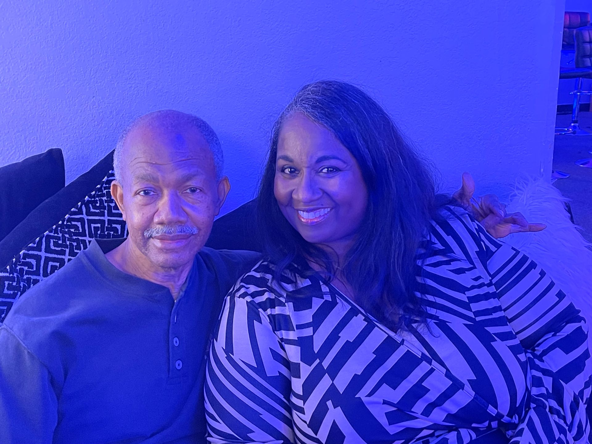 A man and a woman are posing for a picture while sitting on a couch.