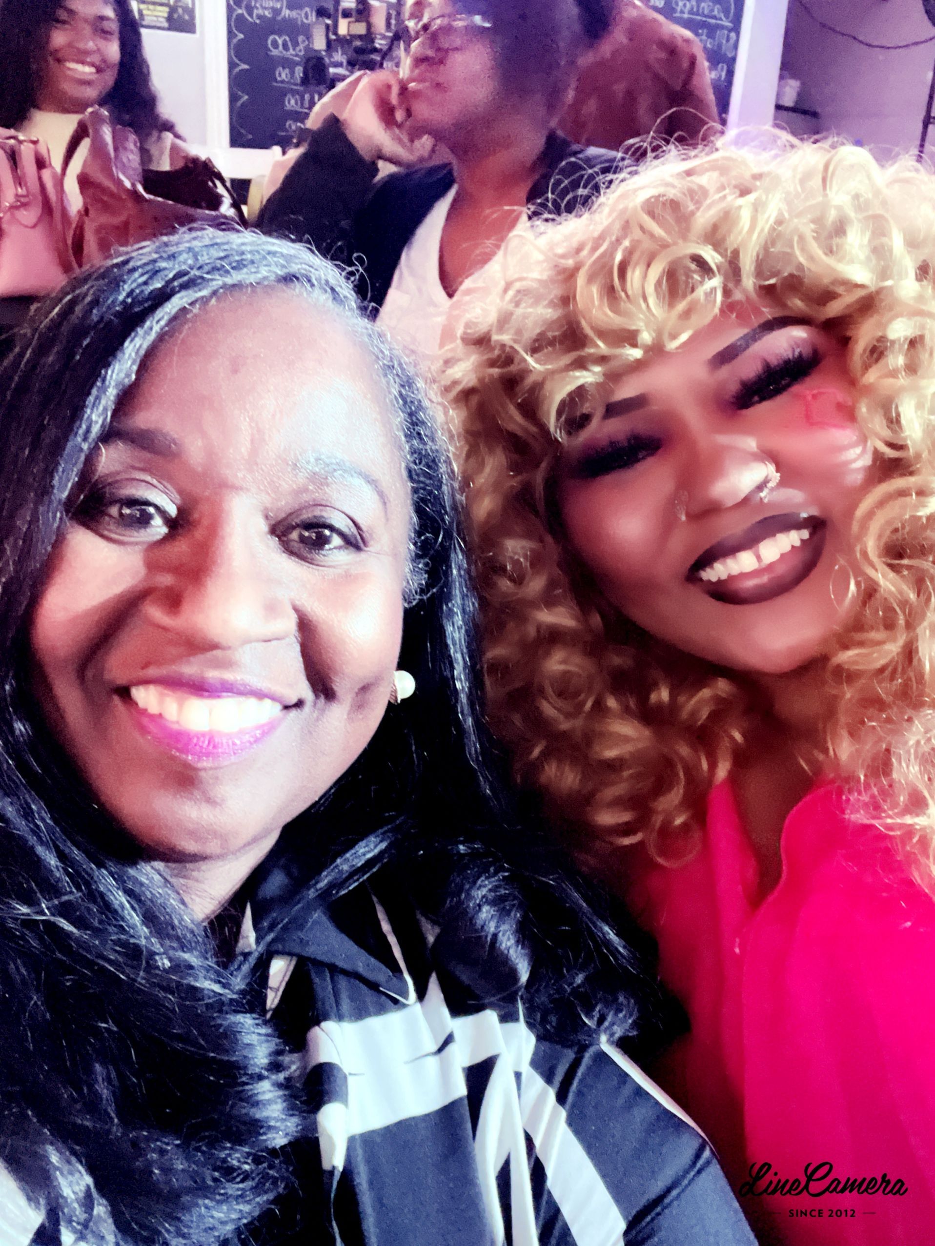 Two women are posing for a picture and one has curly hair