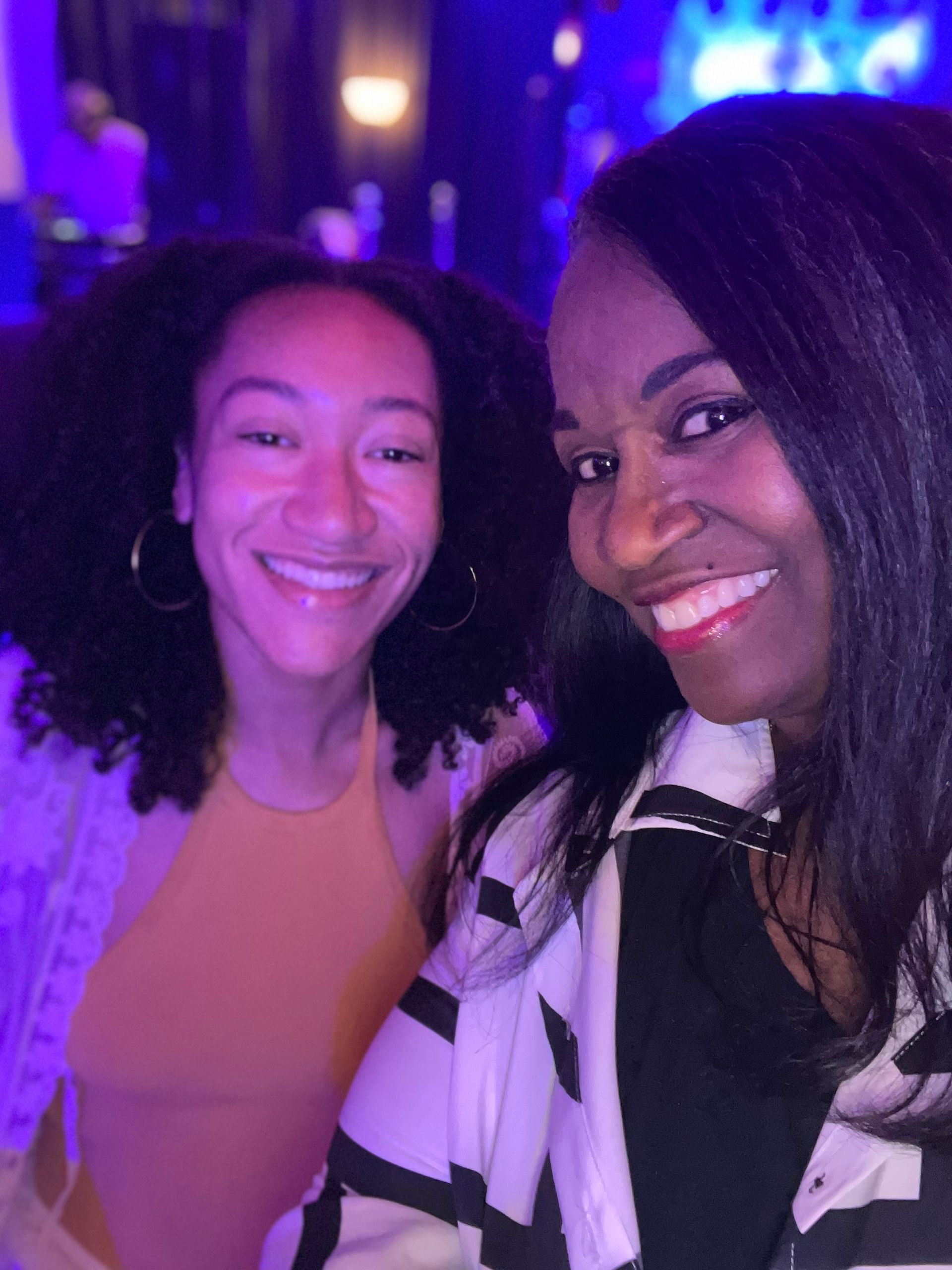 Two women are posing for a picture and smiling for the camera