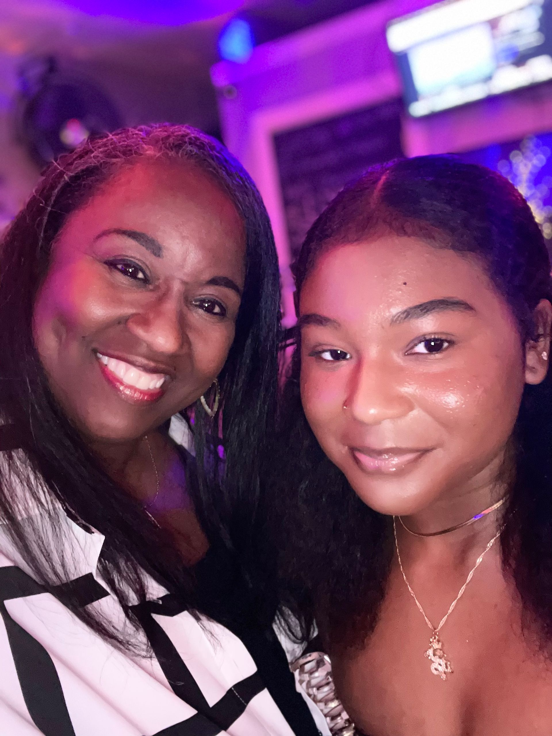 Two women are posing for a picture together and smiling for the camera.