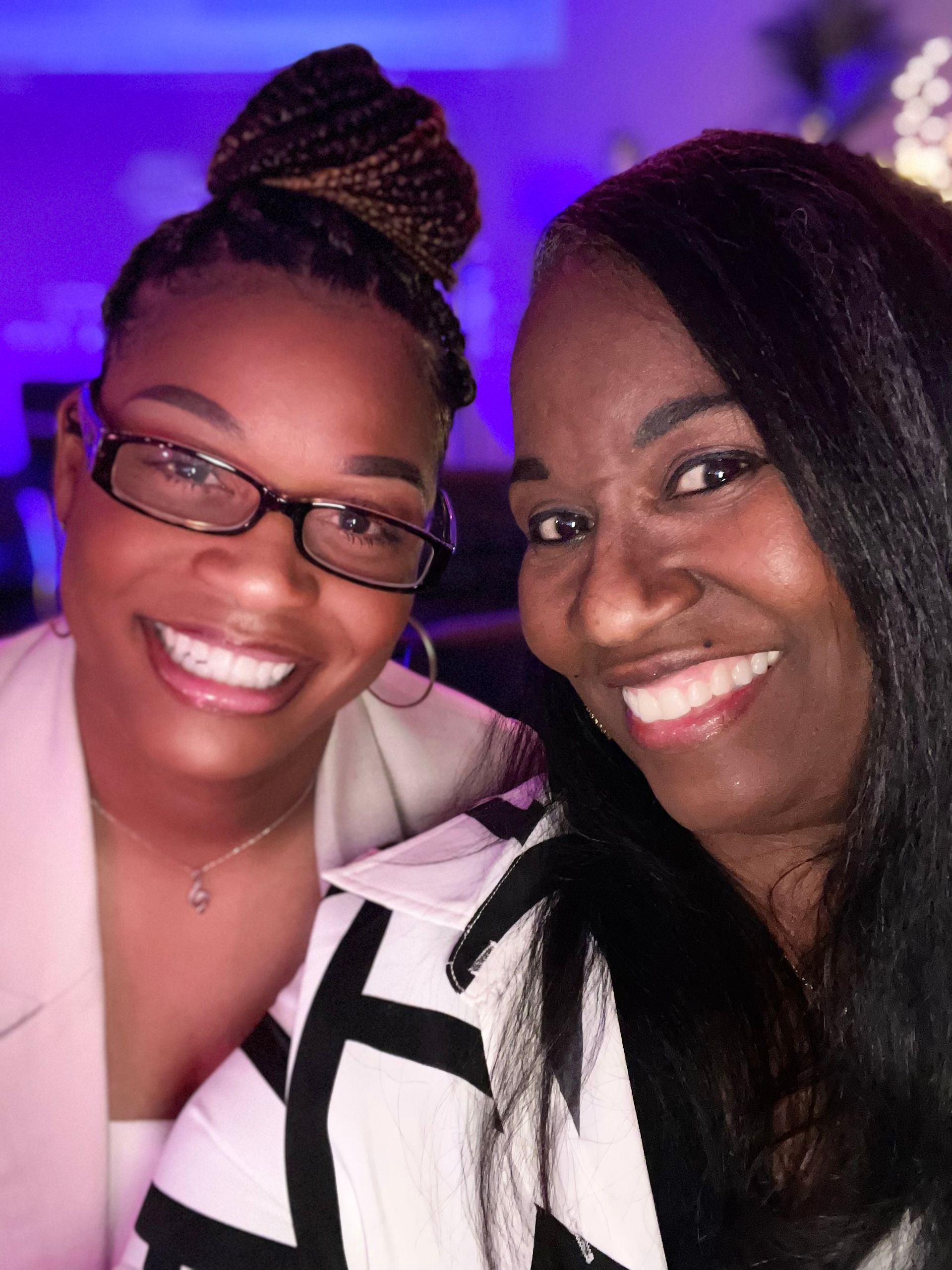 Two women are posing for a picture together and smiling for the camera.