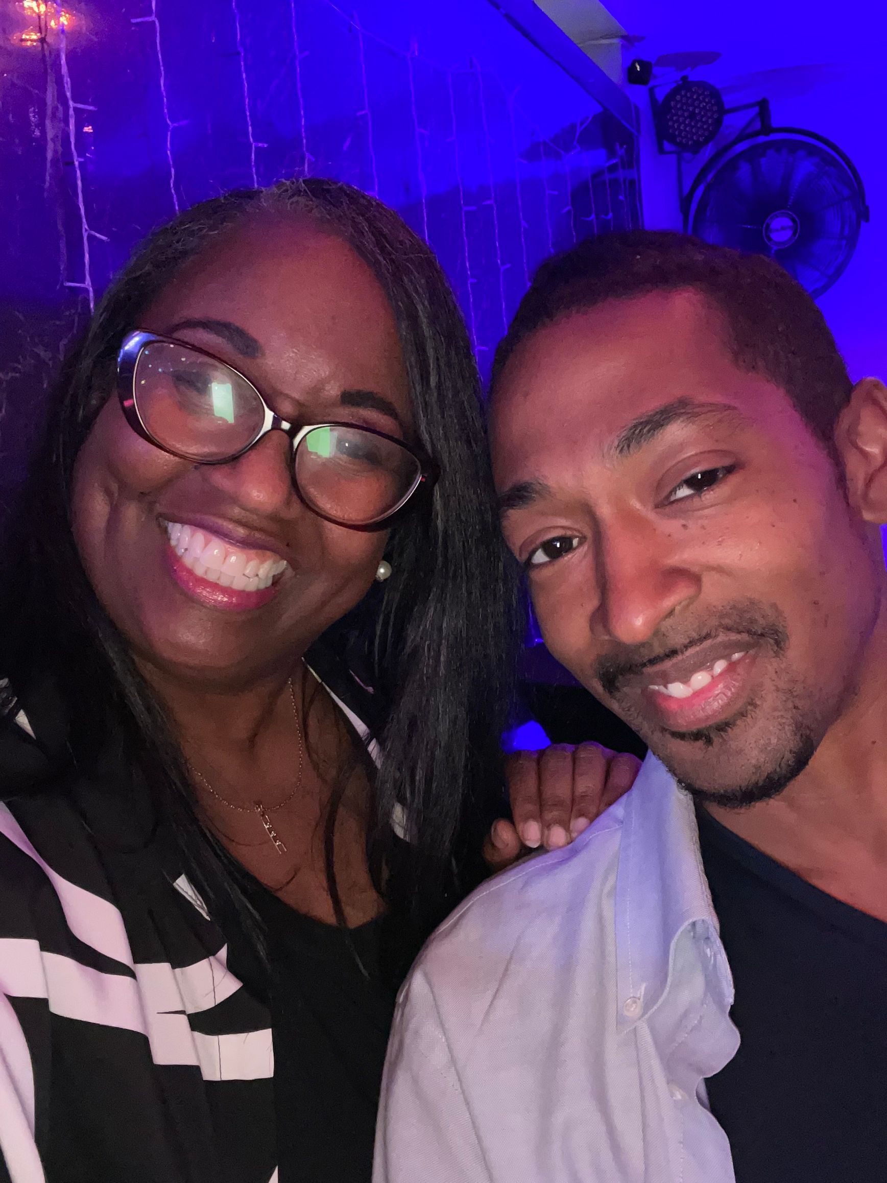 A man and a woman are posing for a picture in a dark room.