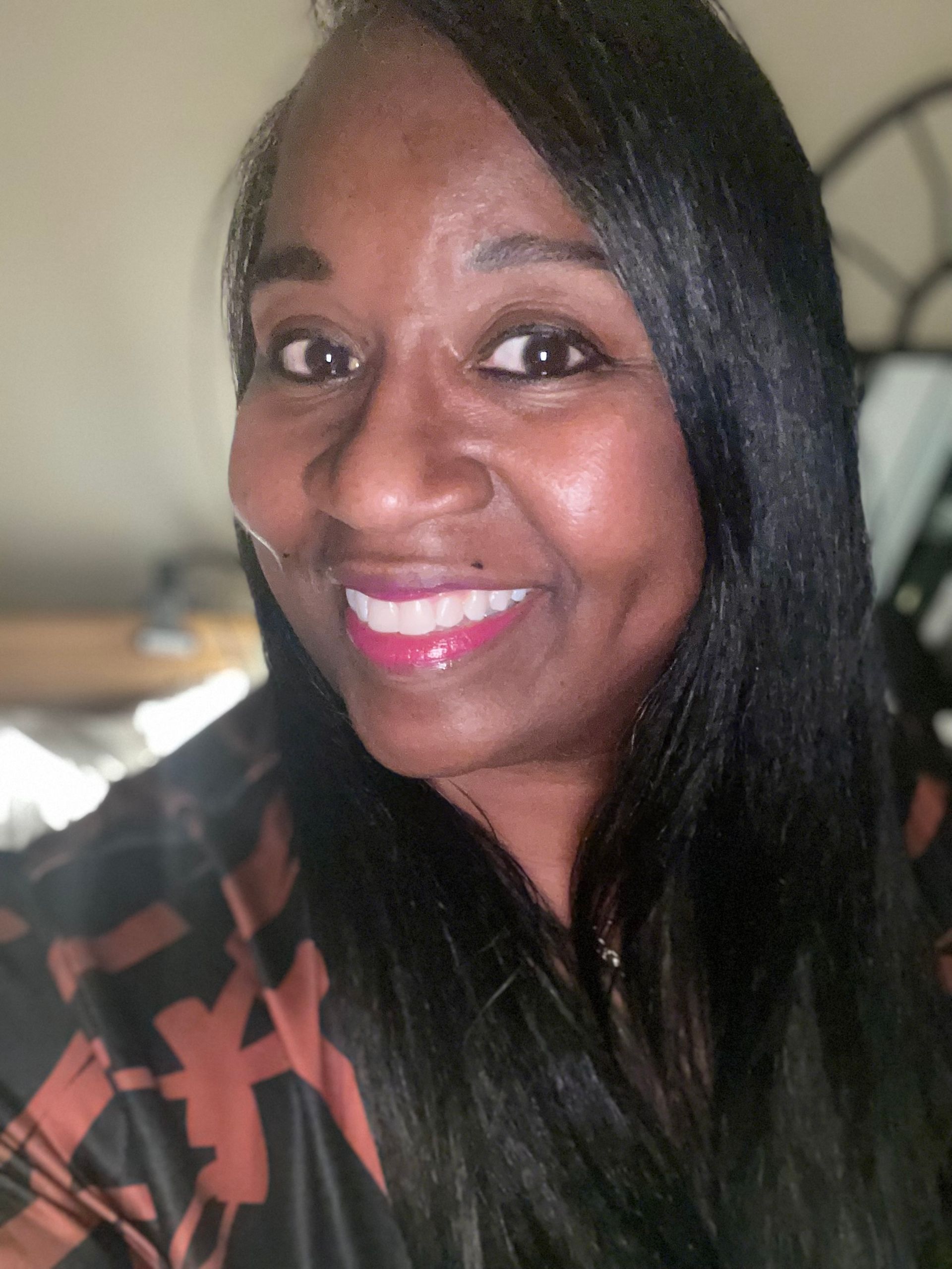 A woman with long black hair is smiling for the camera.