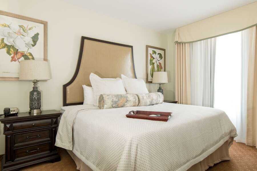 Bedroom with a large bed, two lamps, art, and a window with curtains.