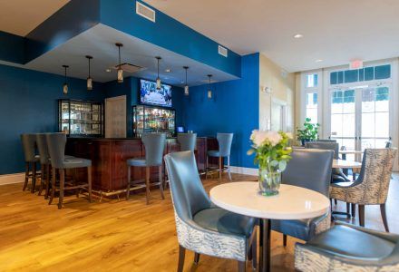 A bar area with stools, a marble-topped table with chairs, and a blue wall.