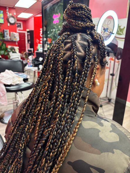 A woman is getting her hair braided in a salon.