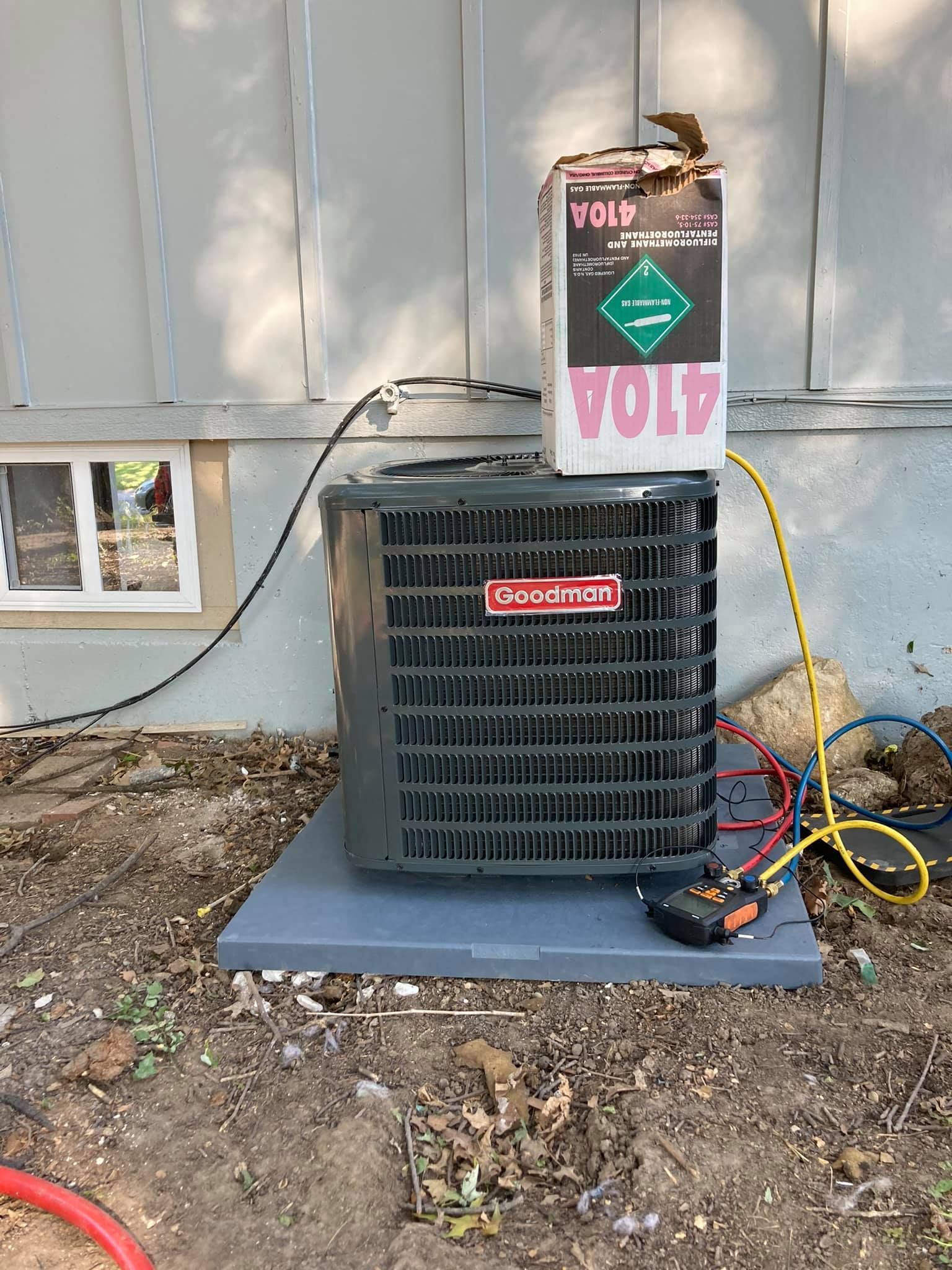 Goodman AC unit undergoing maintenance with refrigerant and diagnostic tools