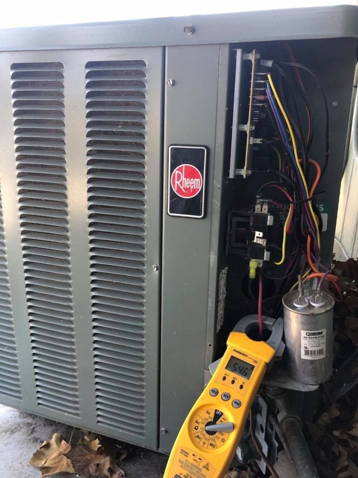 Rheem air conditioning unit with open electrical panel during system diagnostics
