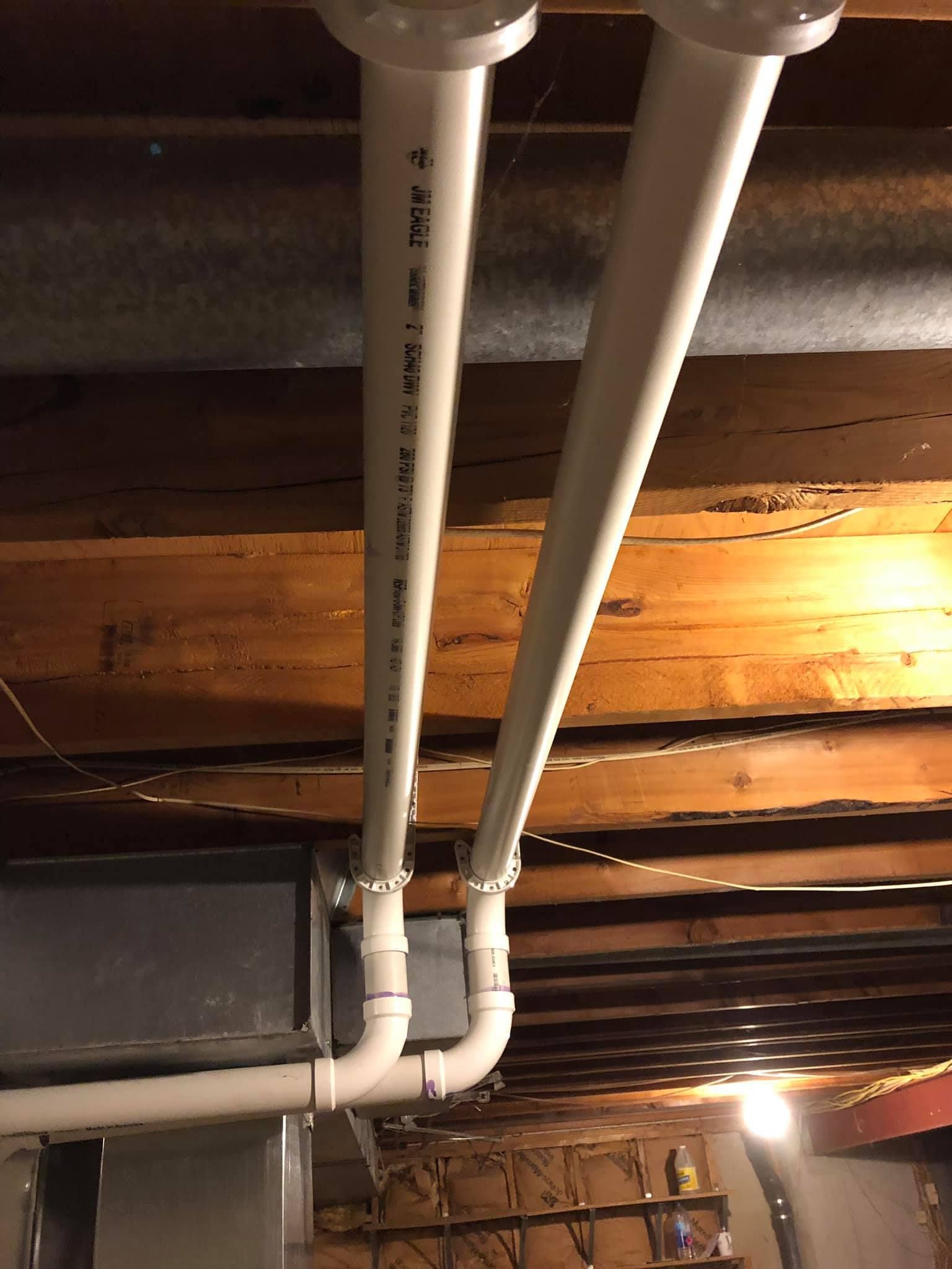 Dual PVC exhaust ventilation pipes for residential HVAC system in basement ceiling