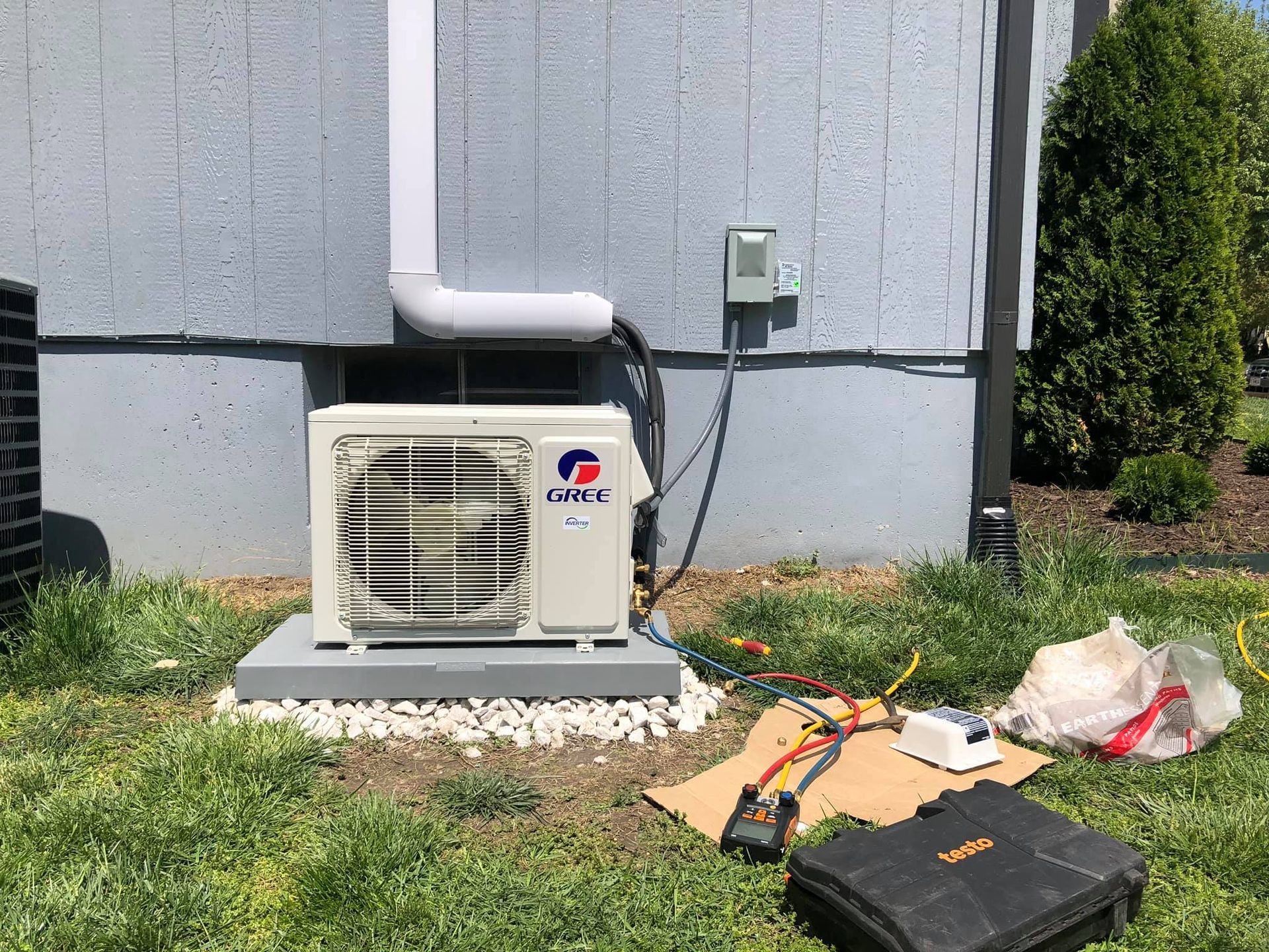 An air conditioner is being installed on the side of a house.