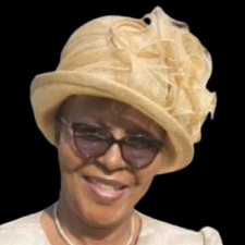 Woman wearing a tan hat and glasses, smiling.