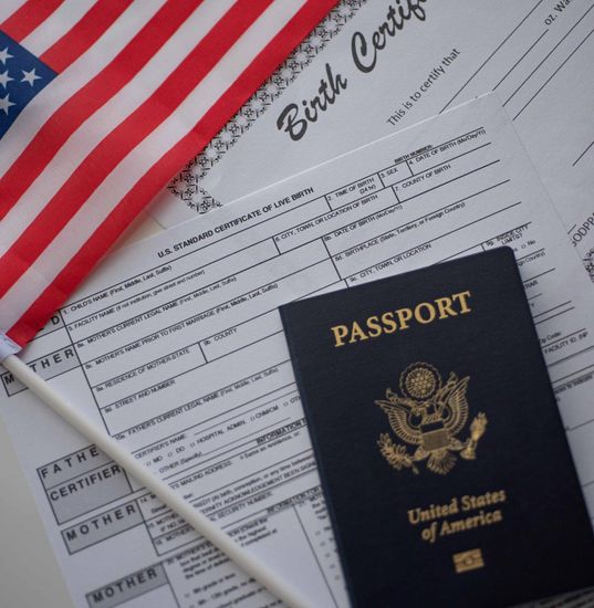 American flag, passport, and birth certificate on a white surface, symbolizing US citizenship.