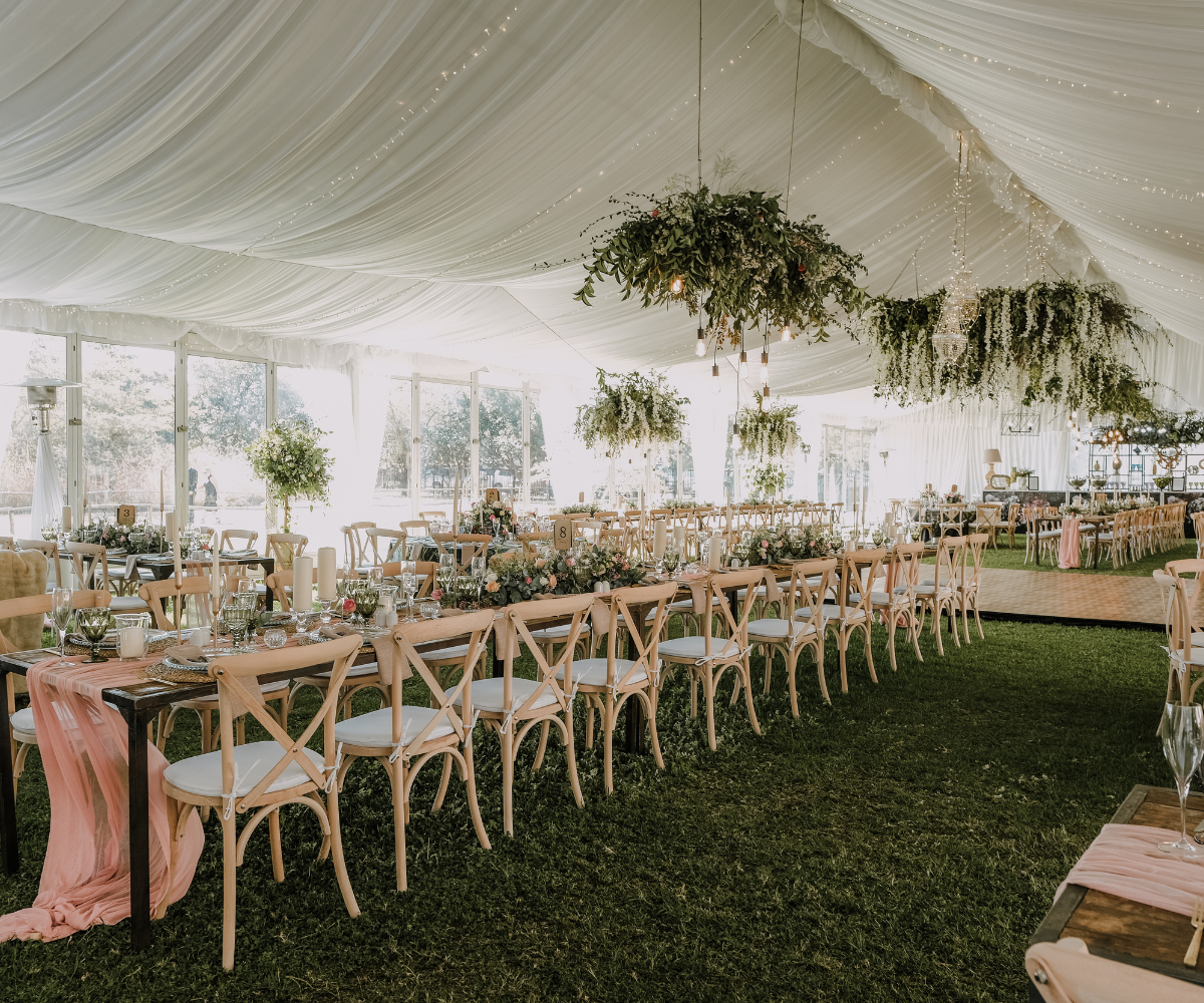 A tent with tables and chairs set up for a wedding reception.