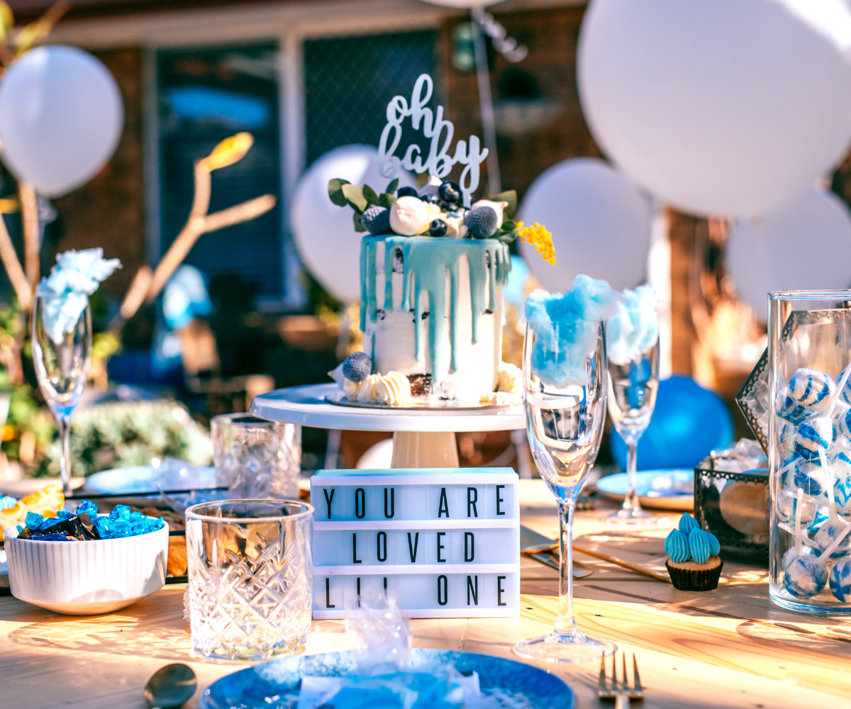 A table set for a baby shower with plates , glasses , and a cake.