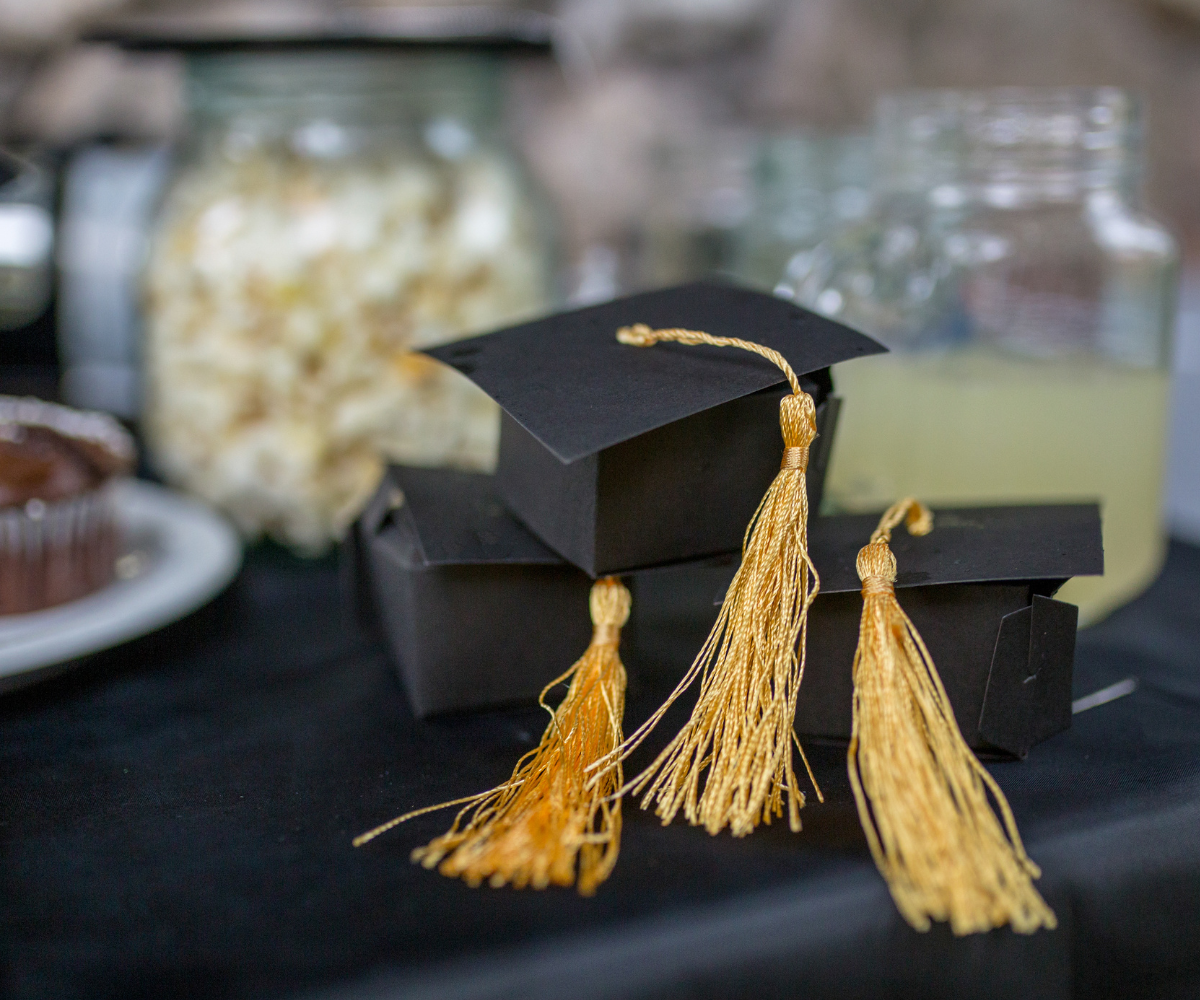 A stack of graduation caps with tassels on a table