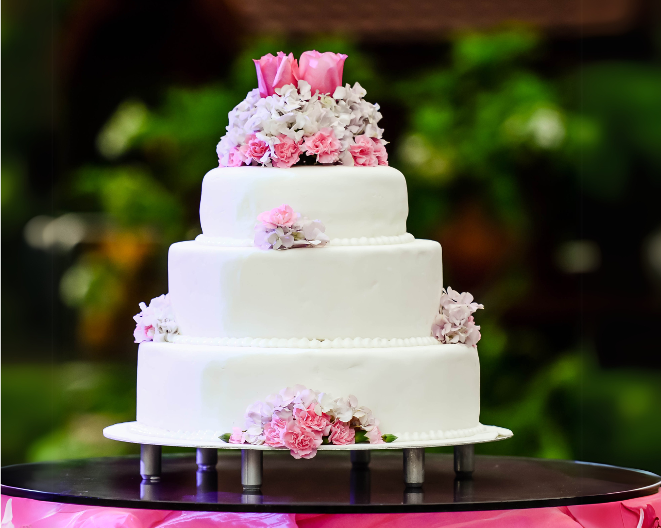A white wedding cake with pink flowers on top