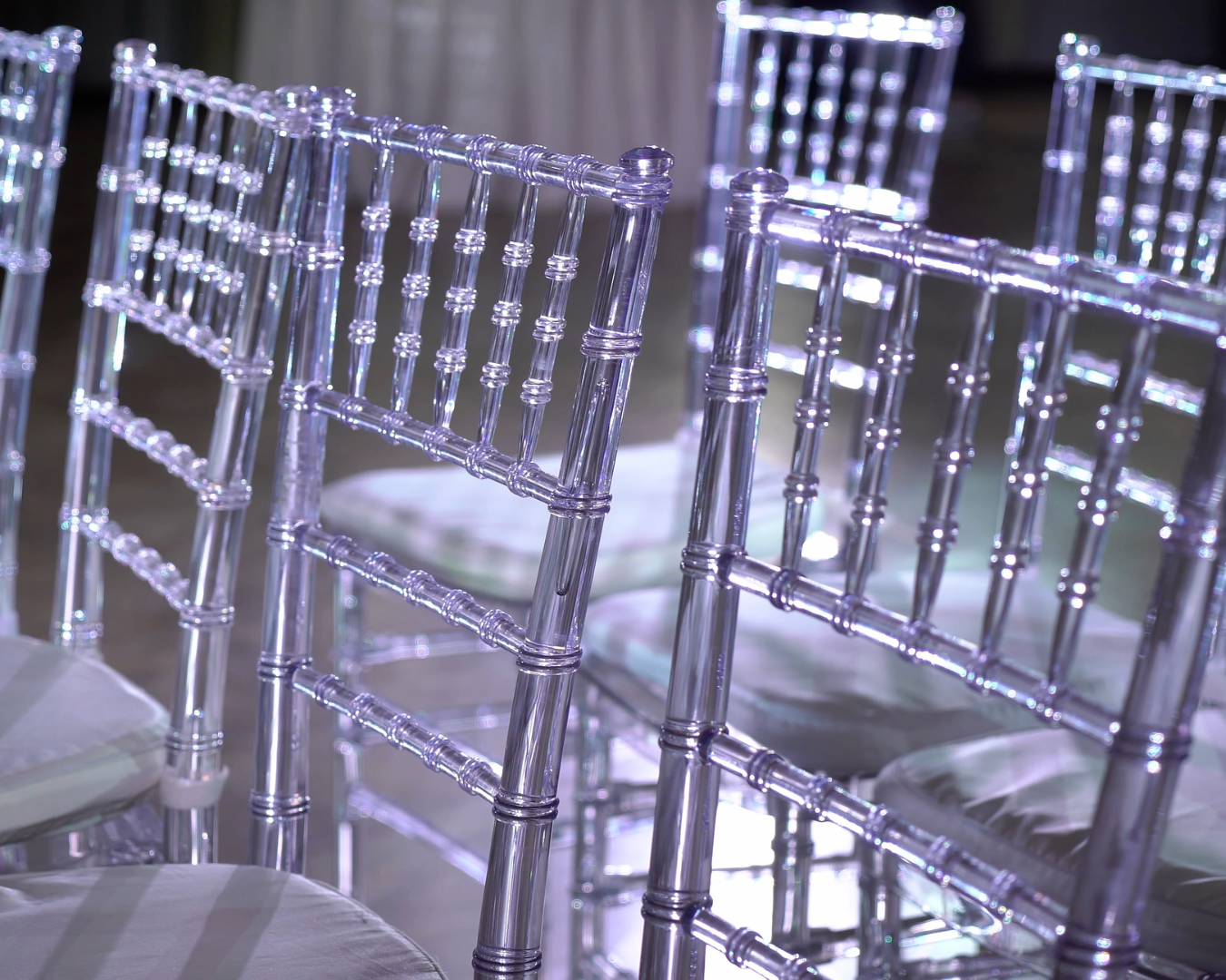 A row of clear plastic chairs sitting next to each other on a table.