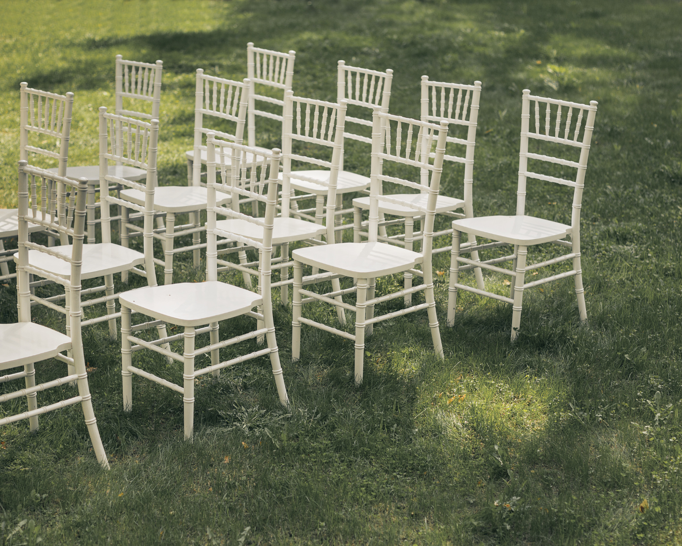 A row of white chairs sitting on top of a lush green field.