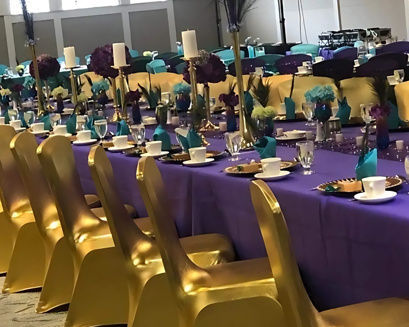 A long table with a purple table cloth and gold chairs