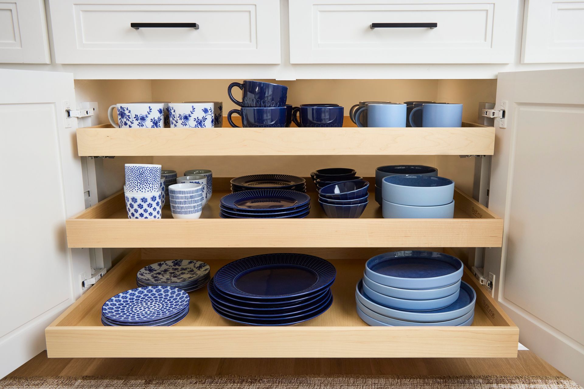 Organized pull-out kitchen drawer with elegant blue dishware, captured by Amy Mikler to showcase fun