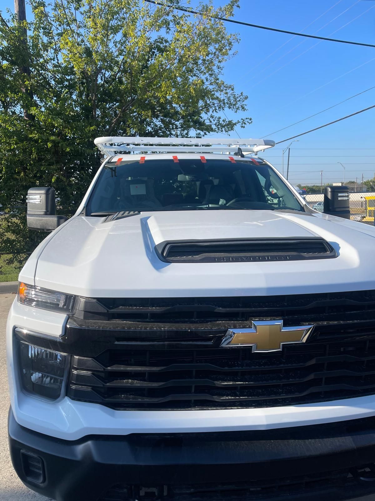 White Chevrolet truck with roof rack, parked outdoors on a sunny day.