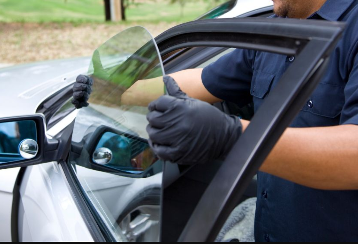 Car windshield replacement with suction cups, shop interior.