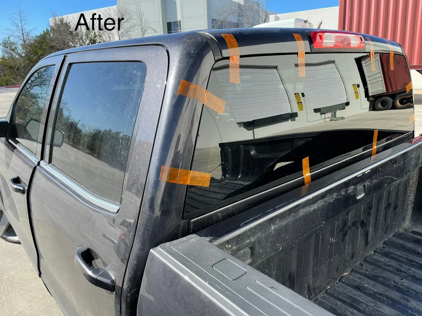 A gray pickup truck with the rear window taped, labeled 