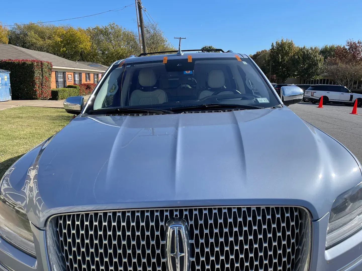 Silver Lincoln Navigator SUV parked in front of a house on a sunny day.