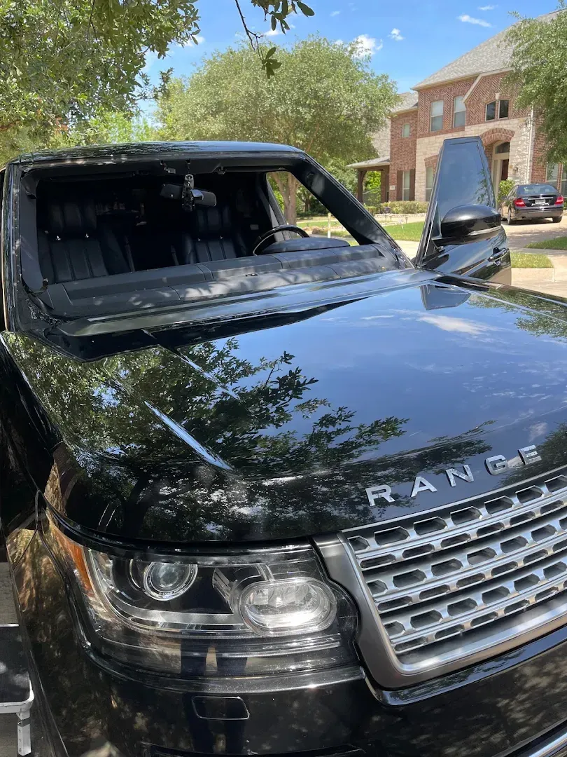 Black Range Rover with windshield and door removed, parked on a street.