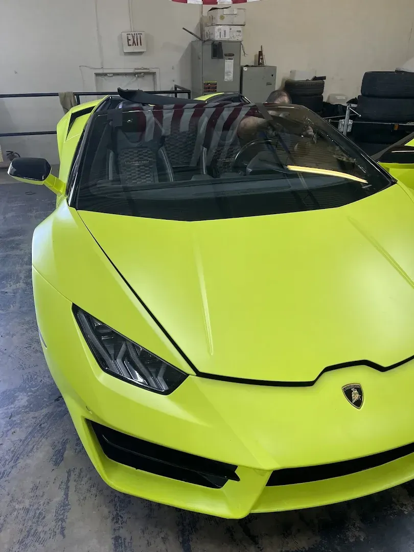 White car with shattered windshield, parked in front of a suburban home.