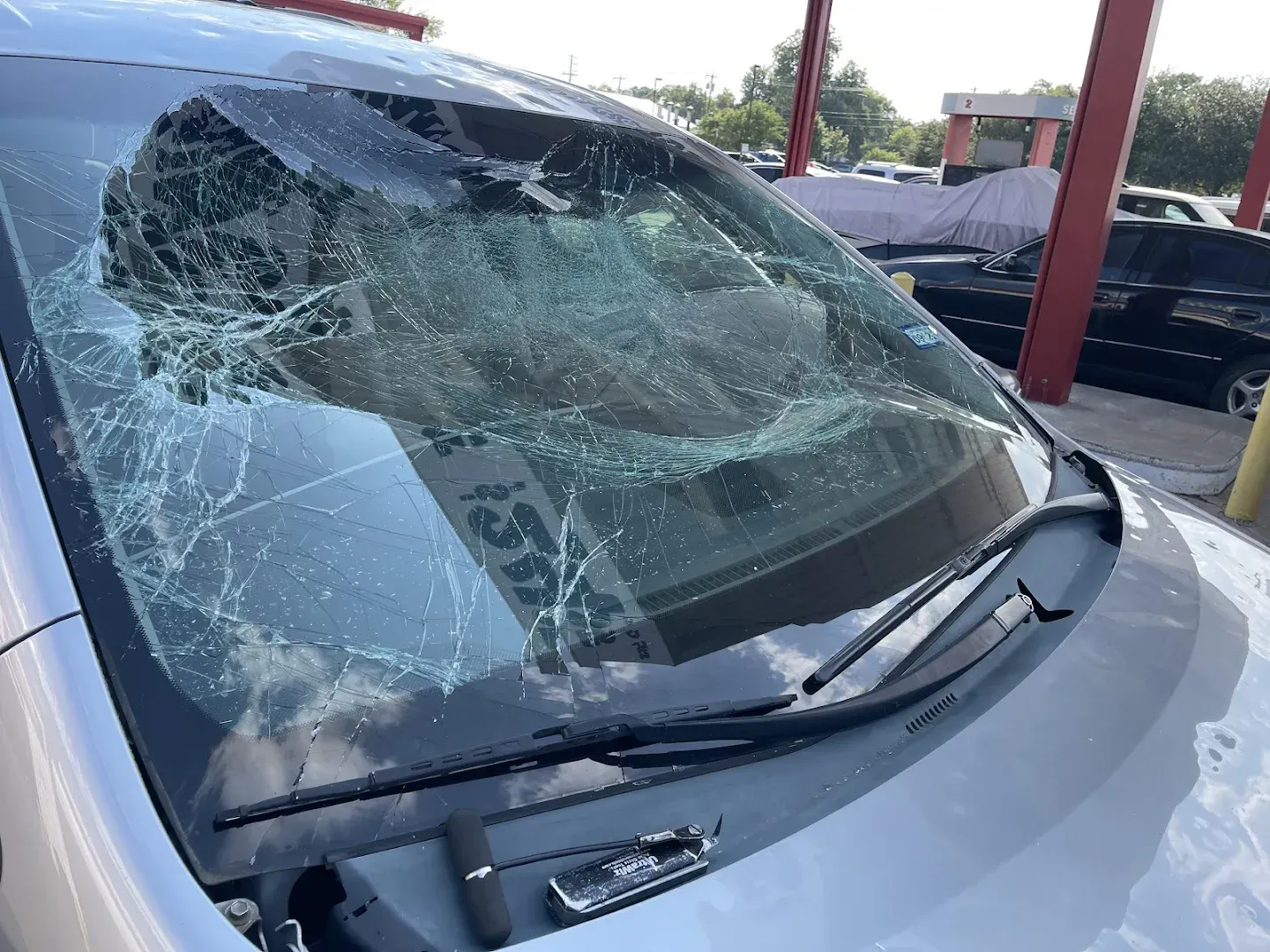 Silver car with shattered windshield, possibly from impact.