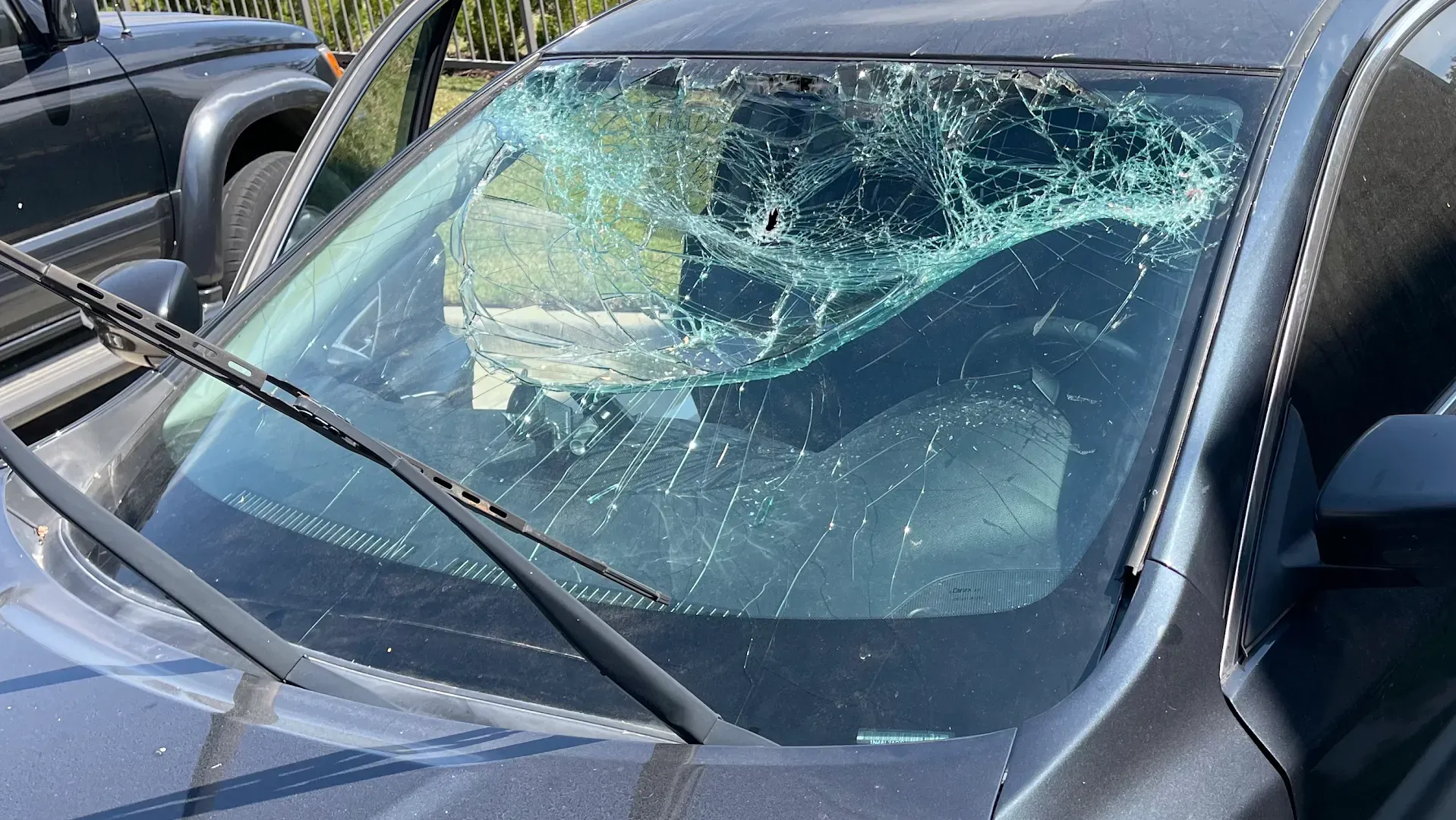 A car with a shattered windshield, wipers in place, possibly after an accident.