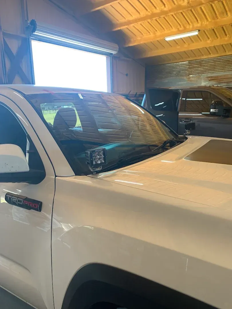 White Toyota truck inside a garage, with a partially opened garage door behind it.