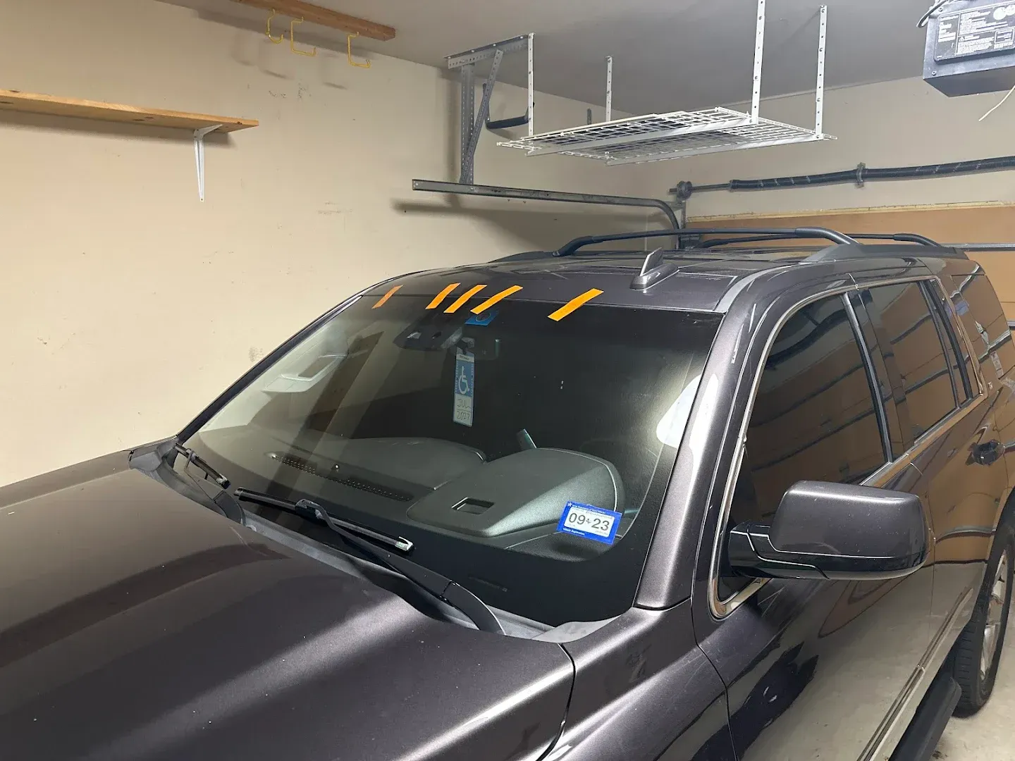 SUV parked in a garage; orange tape on windshield.