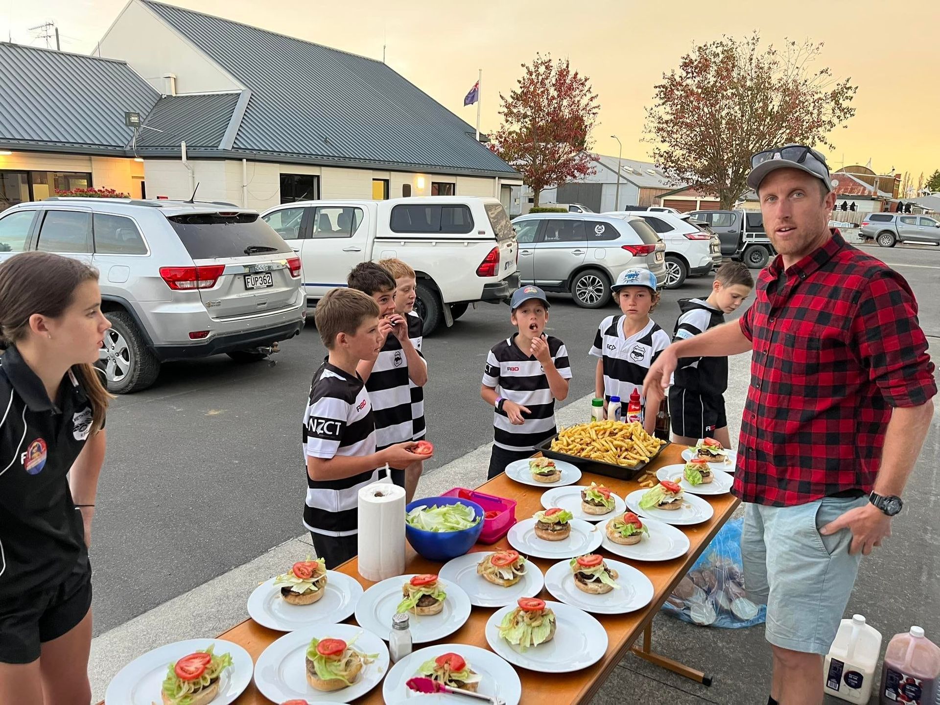 A man in a plaid shirt is standing next to a table with plates of food on it.