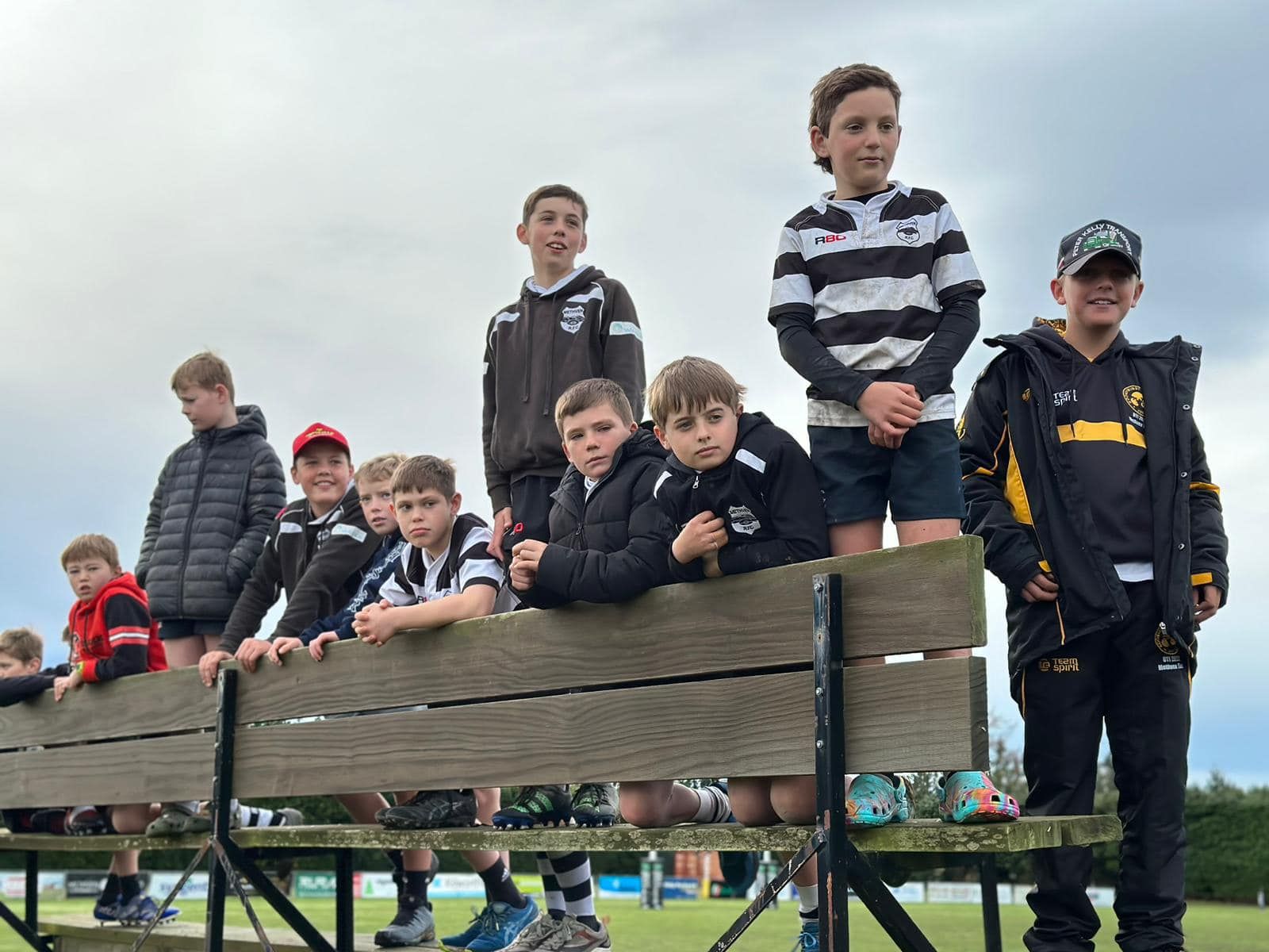 A group of young boys are sitting on a wooden bench