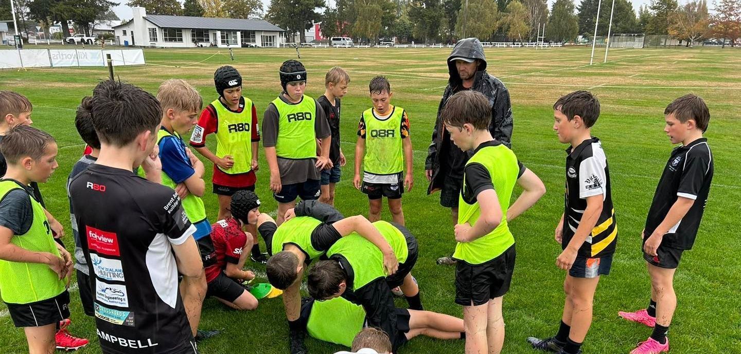 A group of young boys are playing rugby on a field.