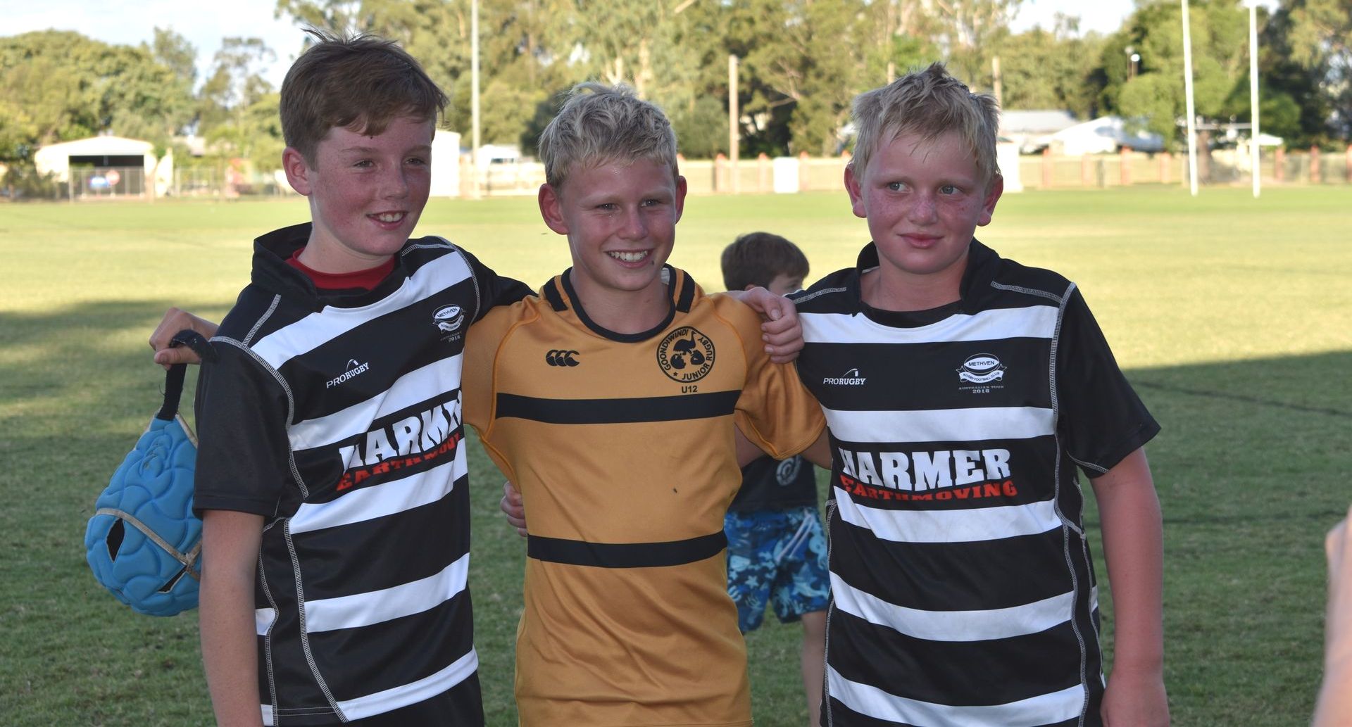 Three boys are posing for a picture with one wearing a shirt that says slamer