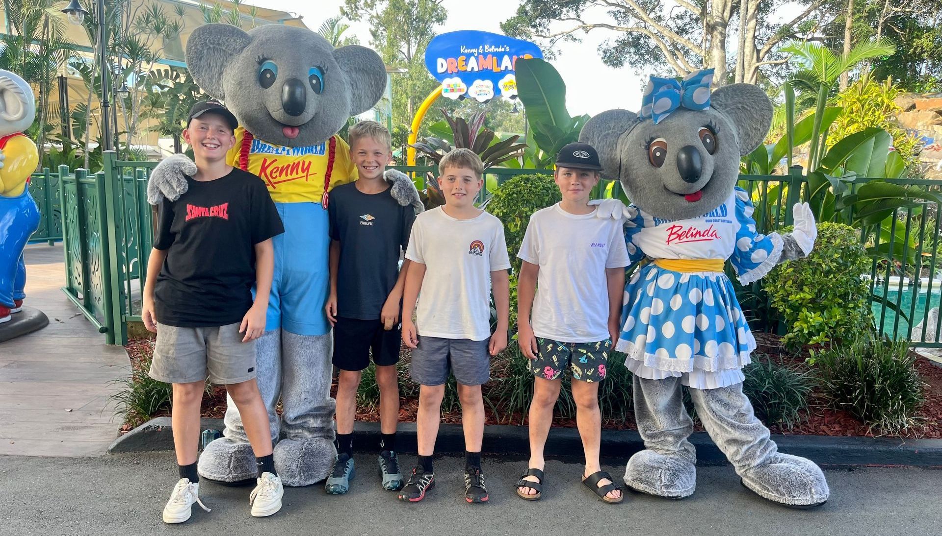 A group of kids are posing for a picture with koala mascots