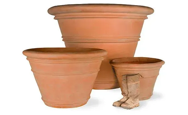 Three terracotta flower pots of varying sizes, with worn brown boots beside the smallest one.