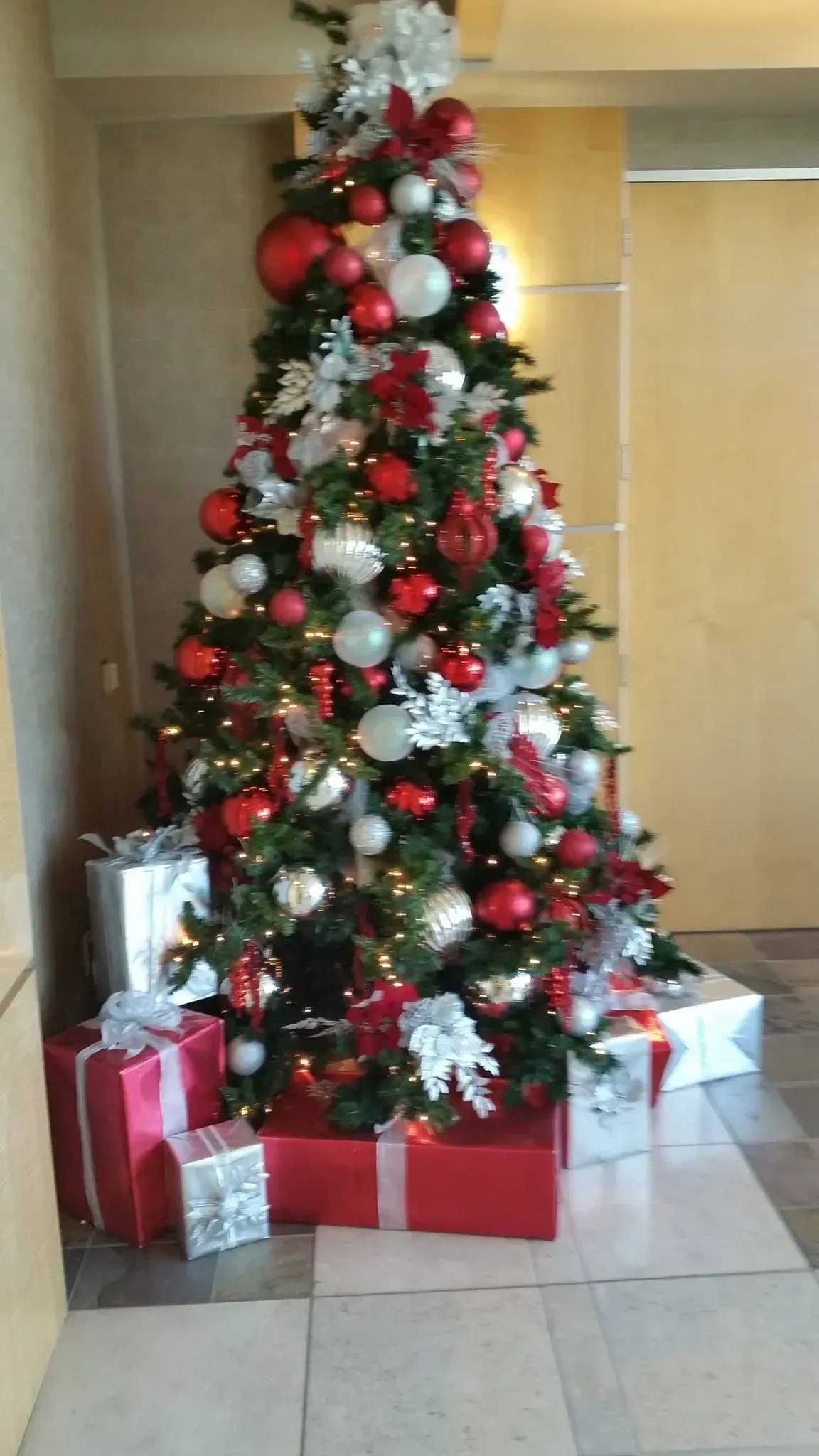 Christmas tree decorated with red and white ornaments, surrounded by wrapped gifts.